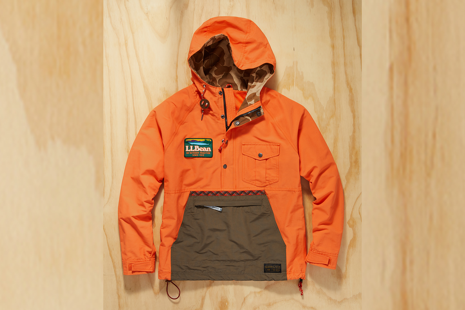 a bright orange anorak with camp detailing on a wood background