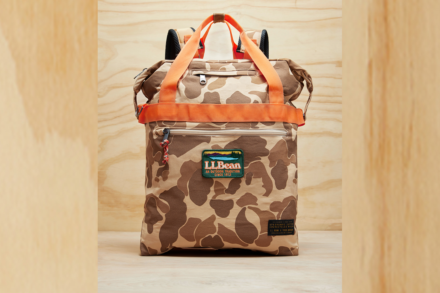 a camp and orange backpack on a wood background