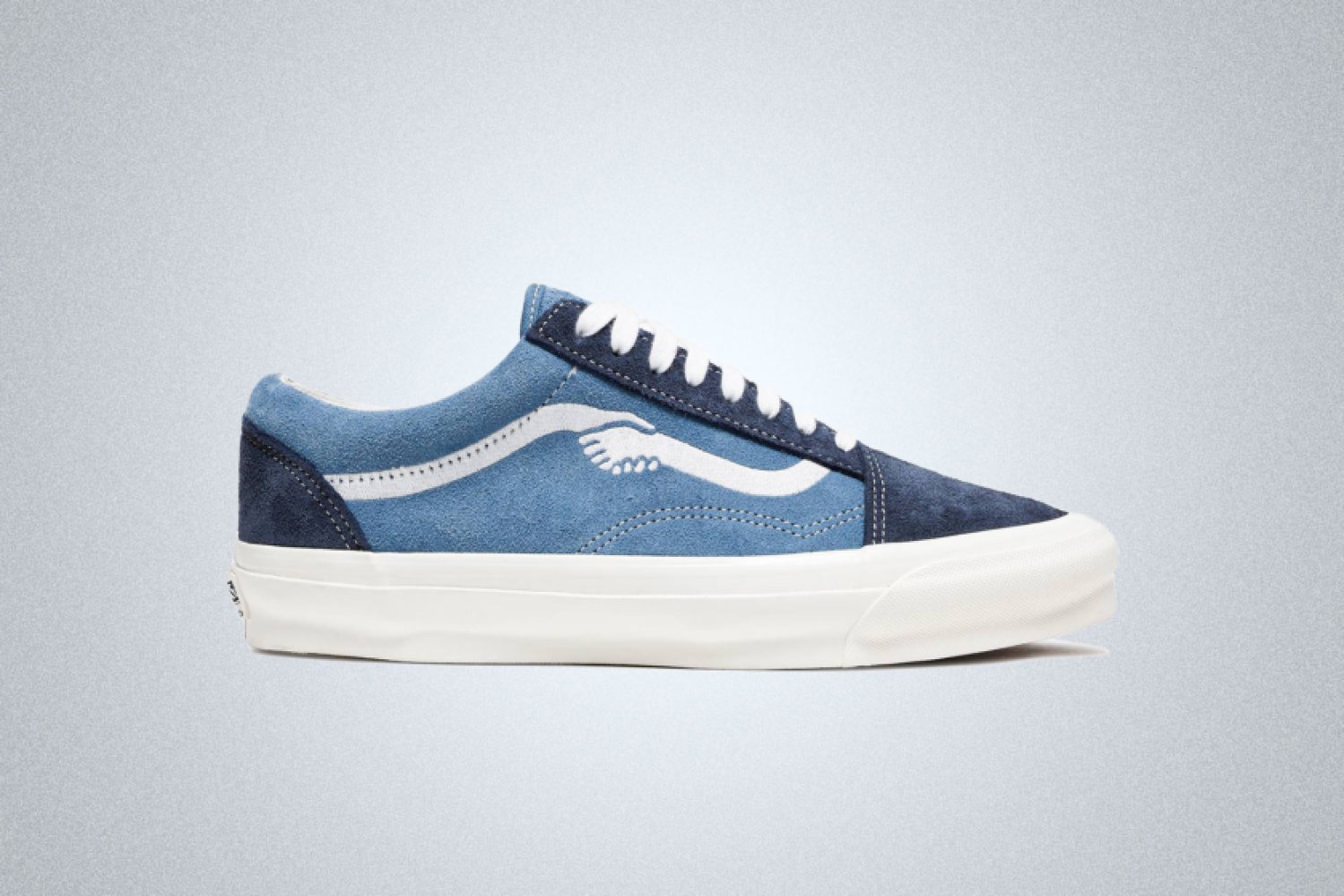a blue Vans x Notre sneaker with hand-holding graphic on a grey background