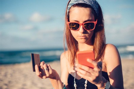 Young woman on the beach phoning the bank for credit card support. Fraud, both in calls and online, is more likely to affect younger people.