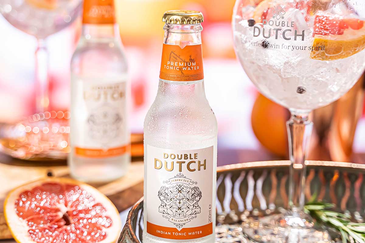 Two bottles of Double Dutch Indian Tonic Water on a table near a glass