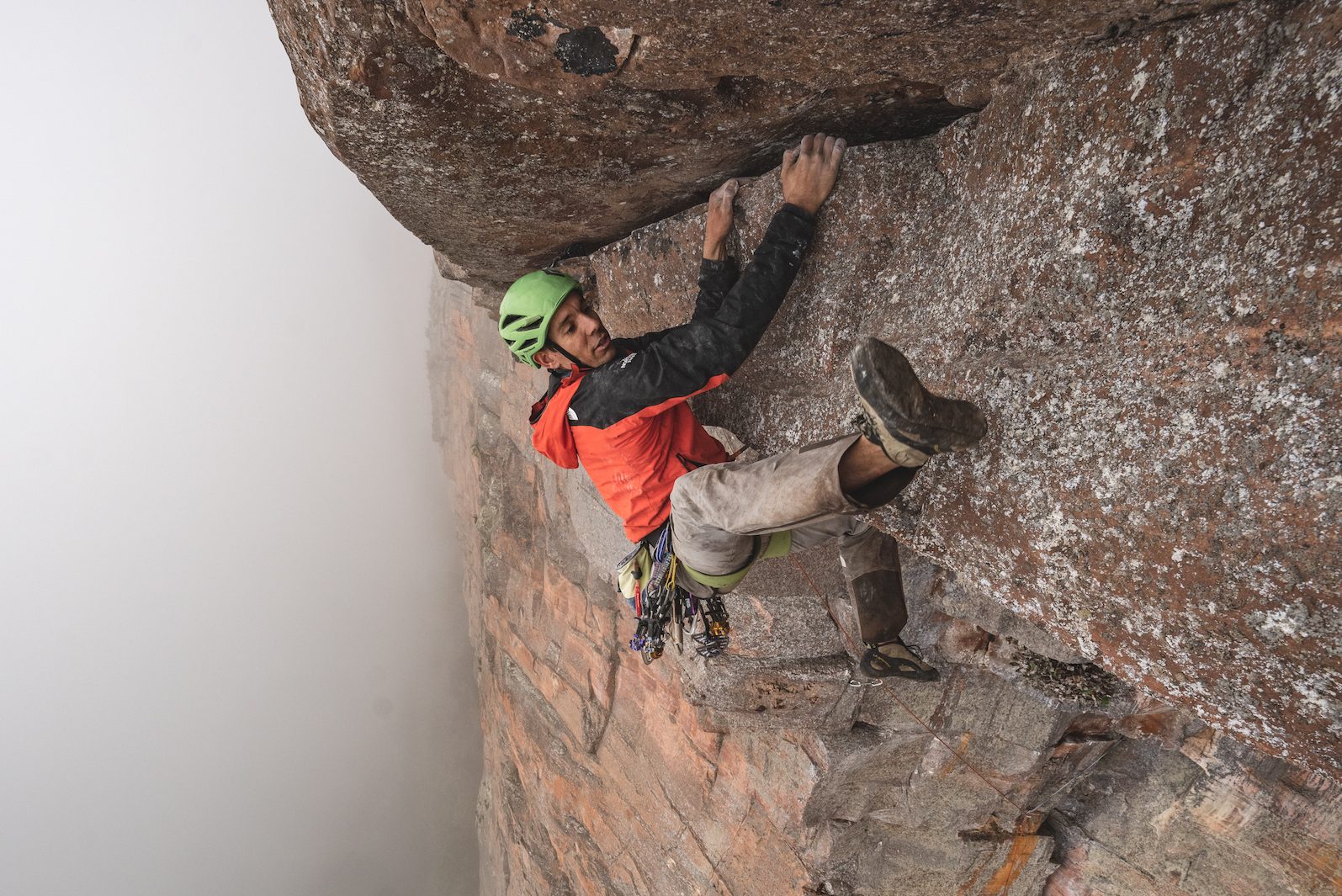 Alex Honnold climbing with a helmet on.