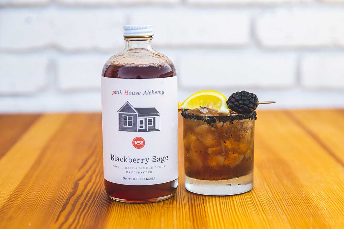 A Deep in the Thicket cocktail with a bottle of Blackberry Sage simple syrup via Pink House Alchemy