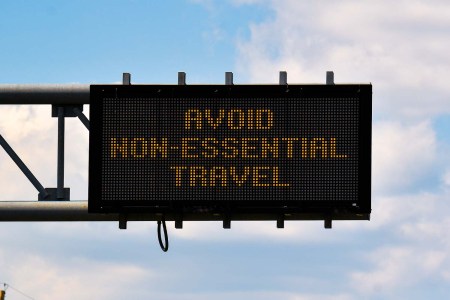 A sign above a road reading "Avoid Non-Essential Travel"
