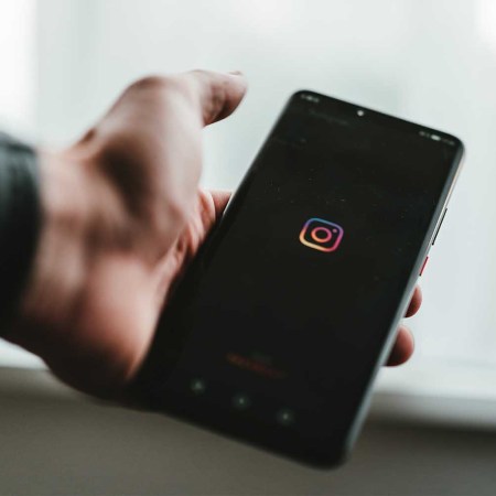 A person holding an iPhone with the Instagram logo.