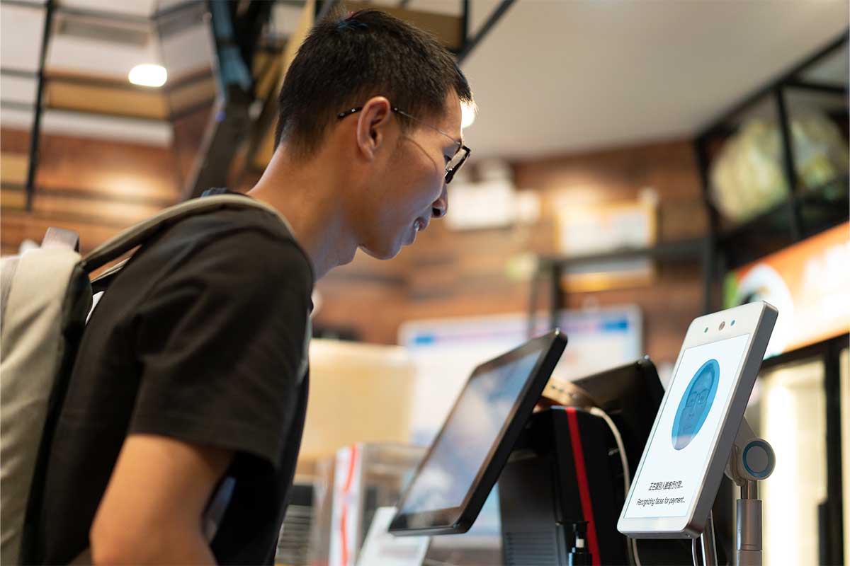 Asian man is using face to make payment on machine - stock photo