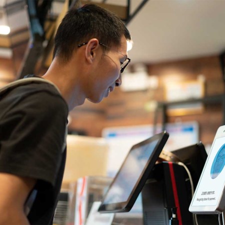 Asian man is using face to make payment on machine - stock photo