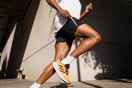 a model in Adidas gear running on concrete