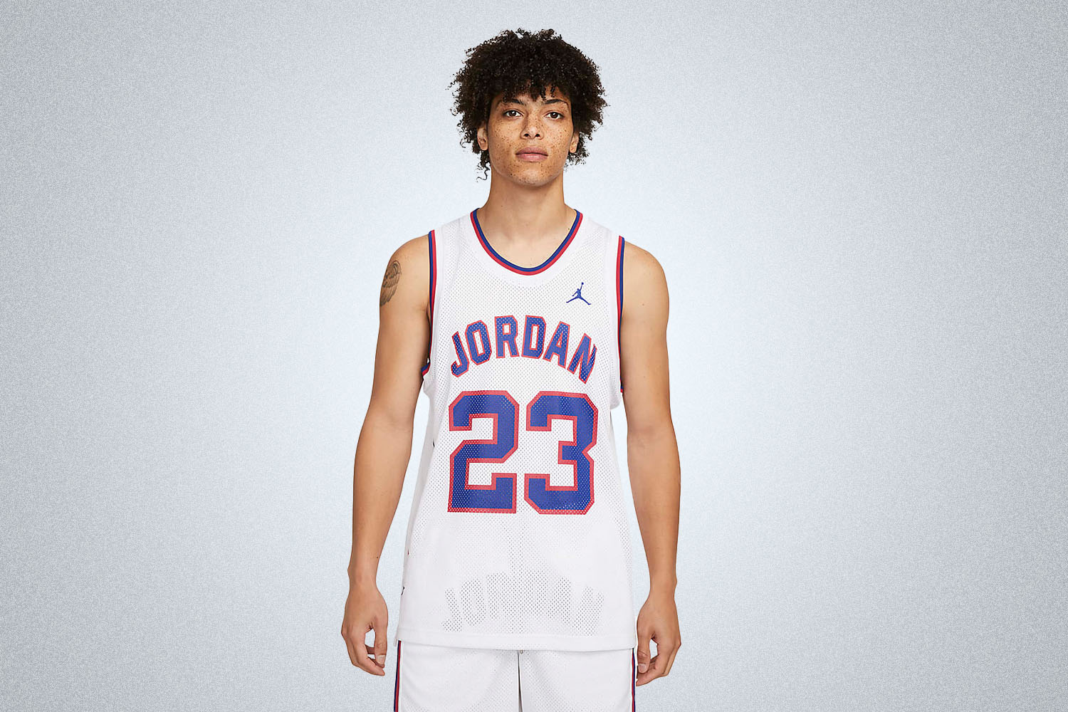 a model in a white "23" Nike Jordan jersey on a grey background