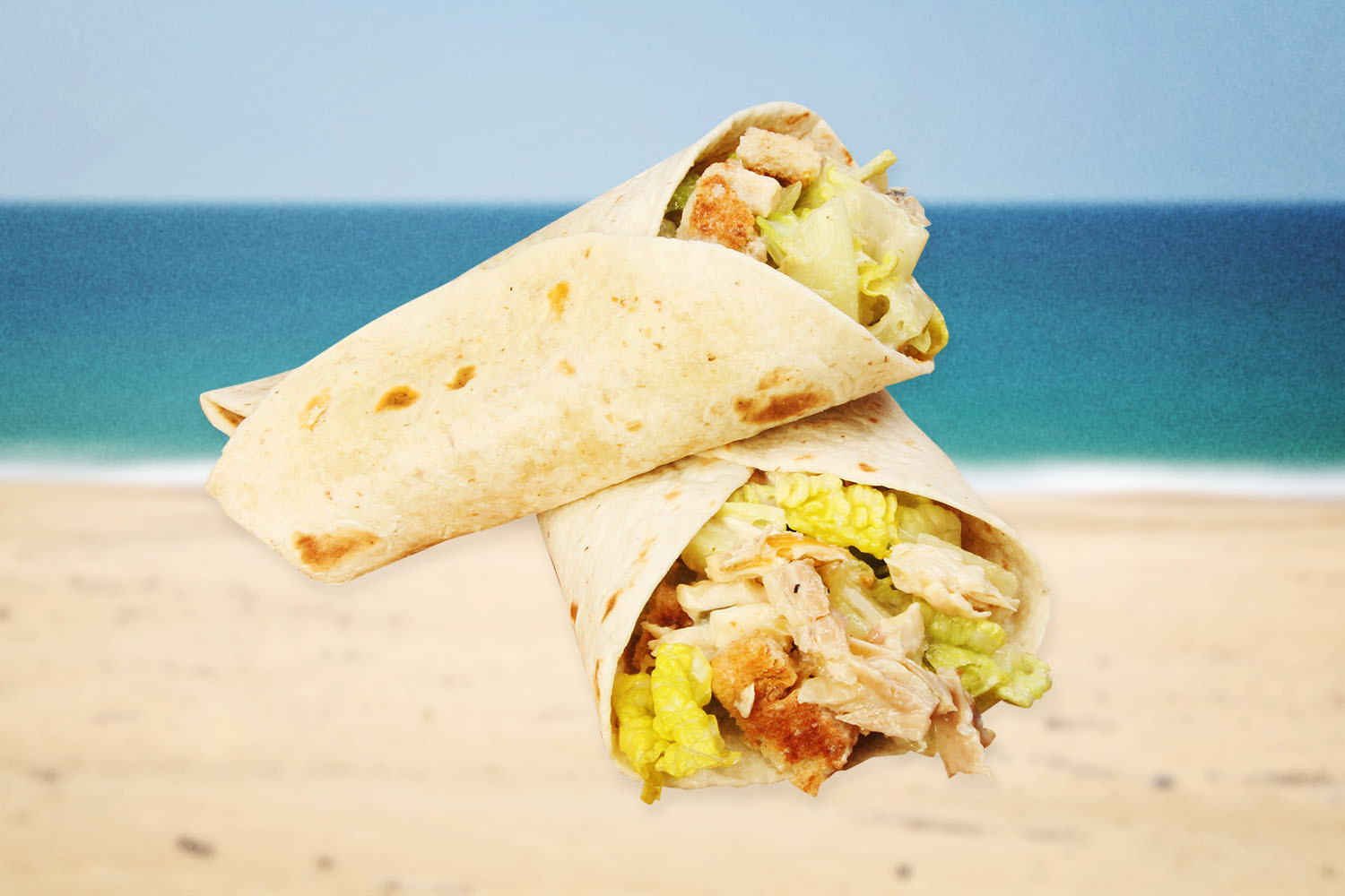 A Caesar salad wrap floating in front of a coastline.