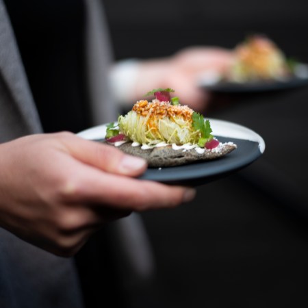 A server holding a plate made by ceramicist Erin Hupp, who makes tableware for top chefs