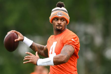 Quarterback Deshaun Watson of the Cleveland Browns throws a pass at camp while wearing an orange jersey and an orange beanie