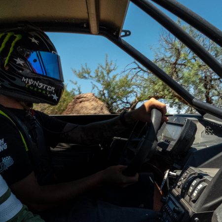 Dakar champ AJ Jones wearing a helmet behind the wheel.