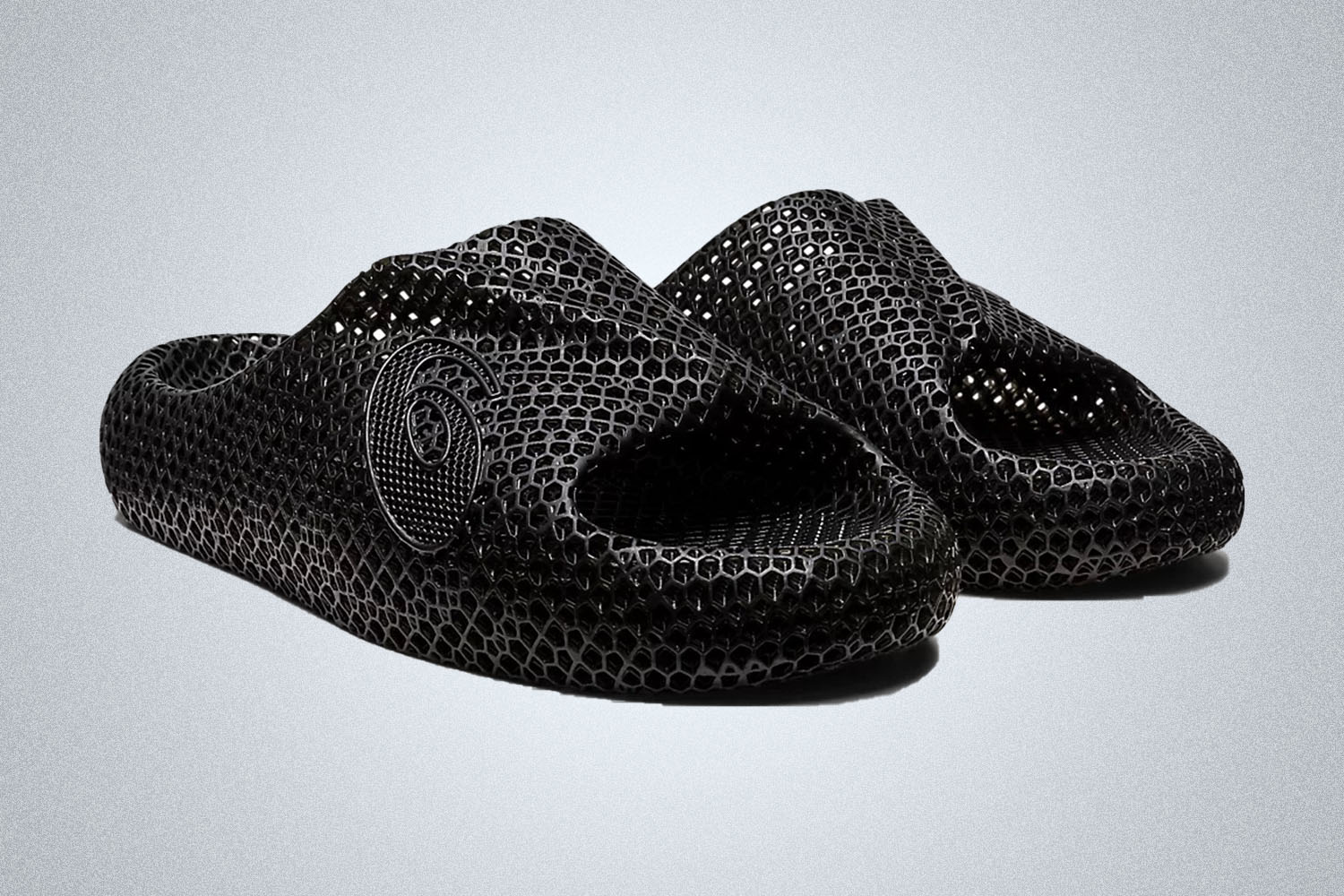 a pair of mesh asics black sandals on a grey background