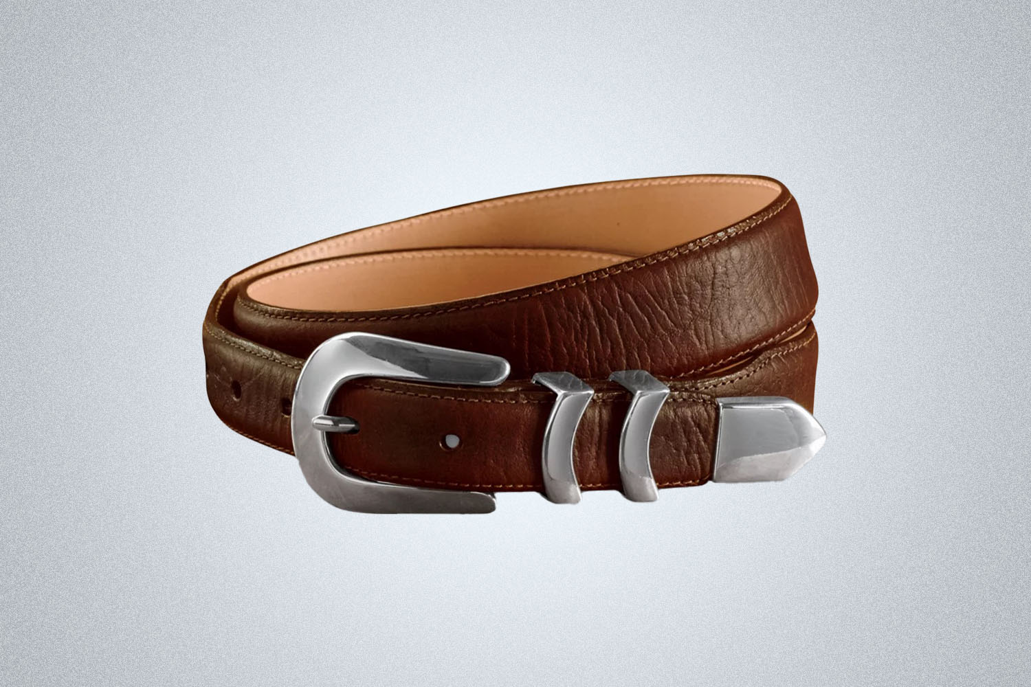 a silver tipped western leather belt from Orvis on a grey background
