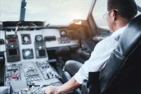 Male pilot sitting in an airplane cabin flying.