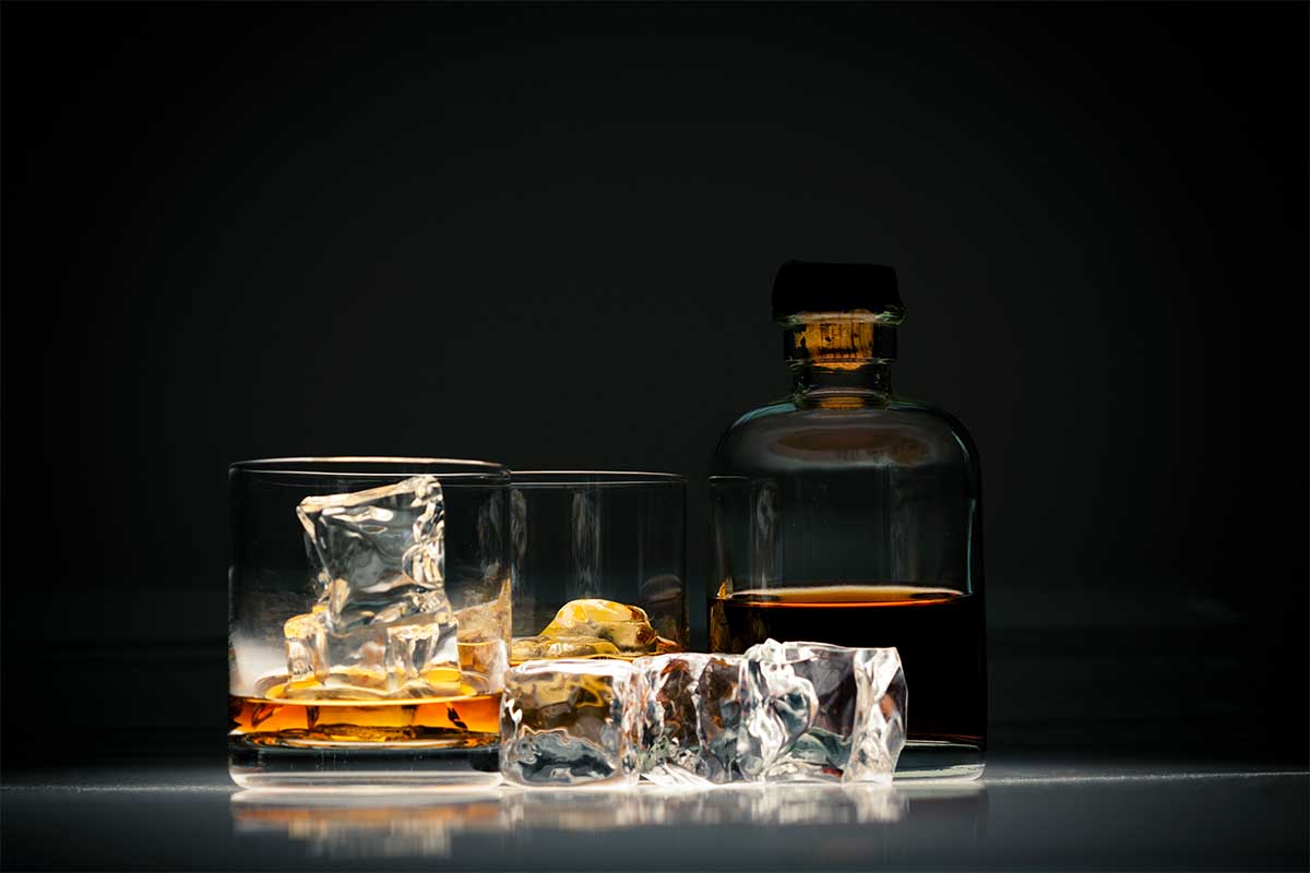 Close-up view of alcoholic beverage on ice in a glass on isolated background. If you see an ice surcharge on your drinks bill, don't worry.