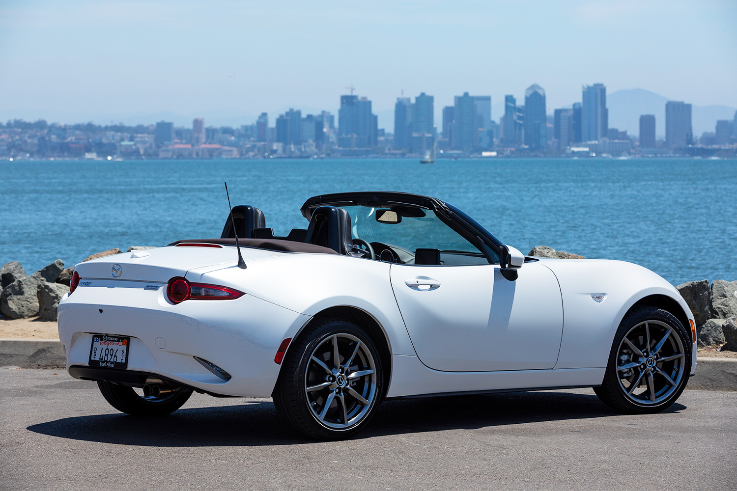 Rear view of a snowflake white Mazda MX-5 Miata sitting next to a bay