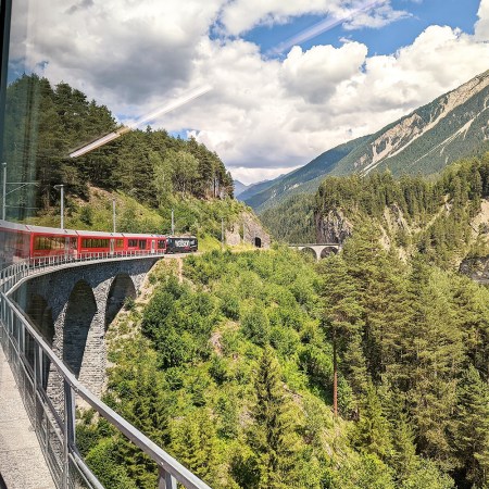 A train going around a curve over a bridge in Switzerland