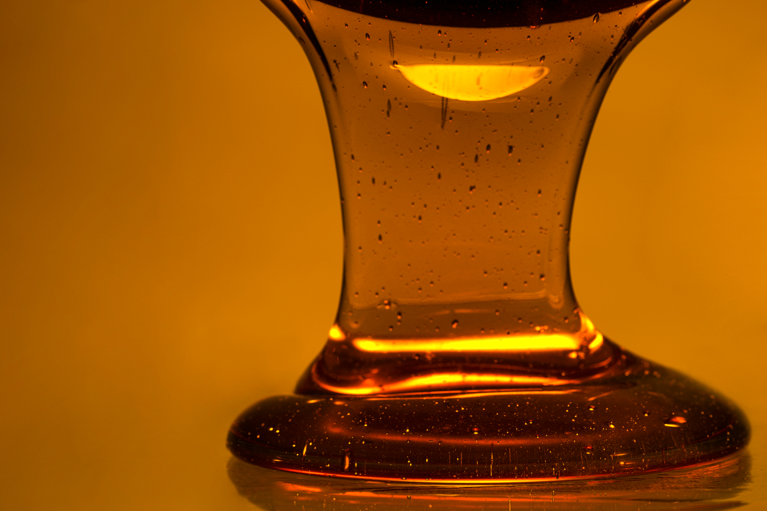 Close up golden honey pour on yellow background
