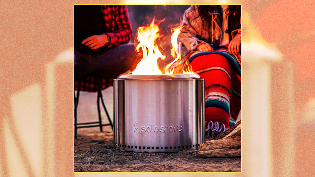 The Solo Stove Bonfire 2.0, with two people sitting in camp chairs behind the roaring smokeless fire pit