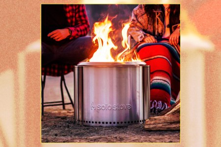 The Solo Stove Bonfire 2.0, with two people sitting in camp chairs behind the roaring smokeless fire pit