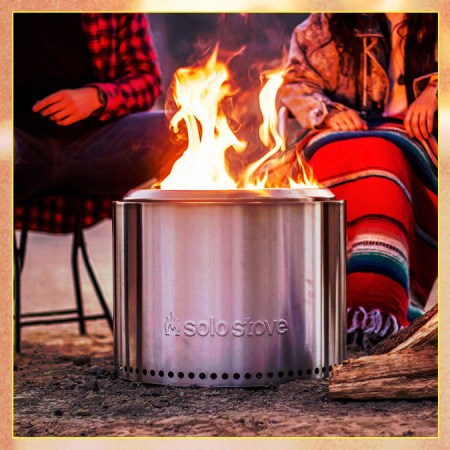 The Solo Stove Bonfire 2.0, with two people sitting in camp chairs behind the roaring smokeless fire pit