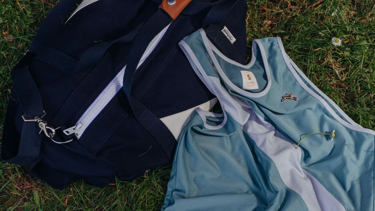 a tracksmith navy bag and blue tank top on grass