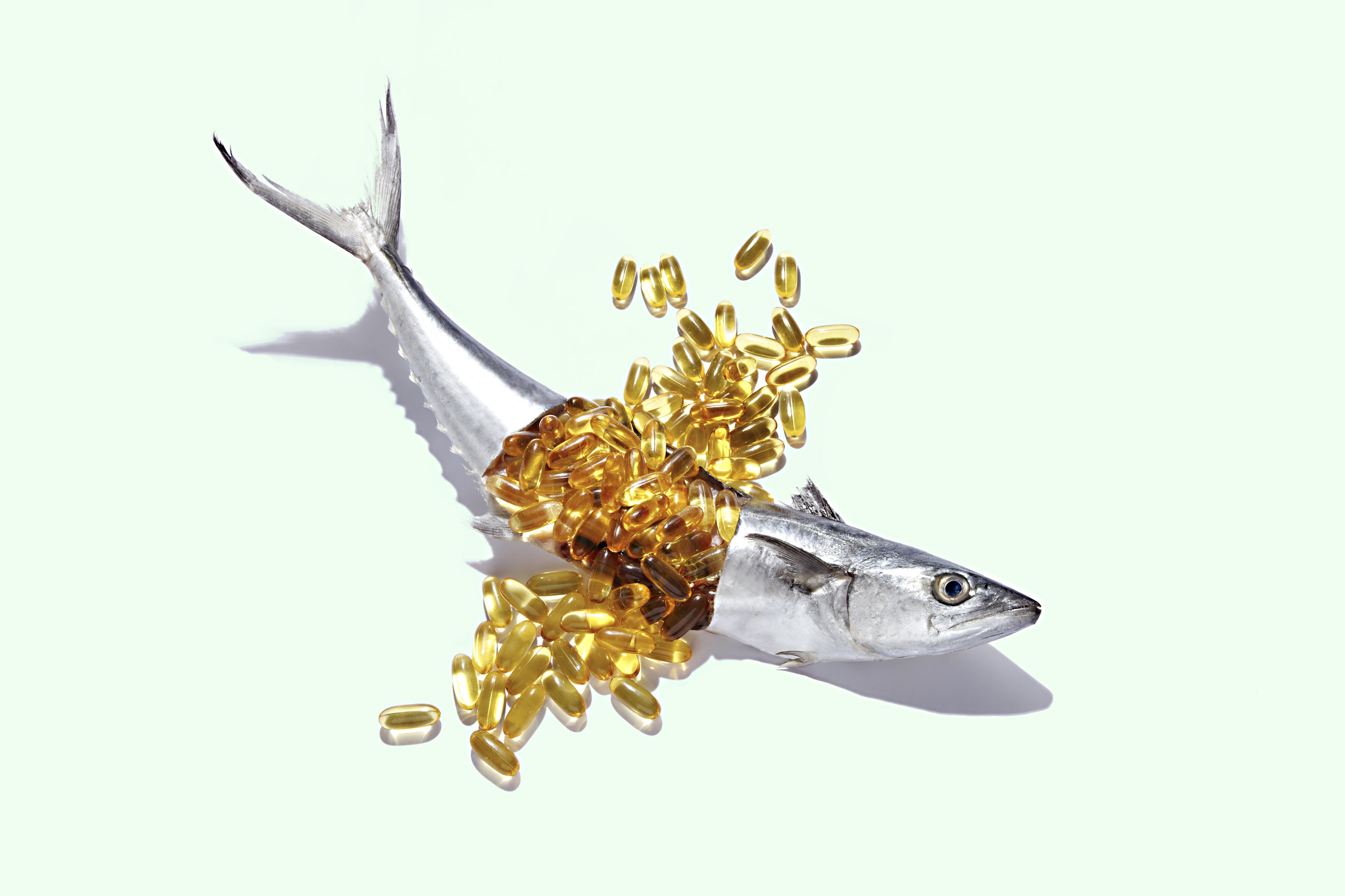 A fish cut open to reveal a dozen fish oil capsules.