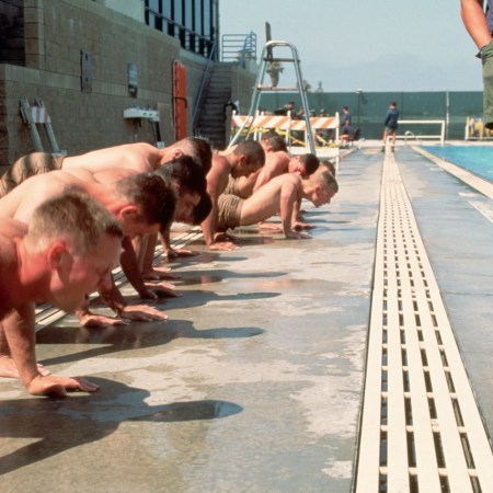 A group of Navy SEAL candidates performing push-ups next to a pool.