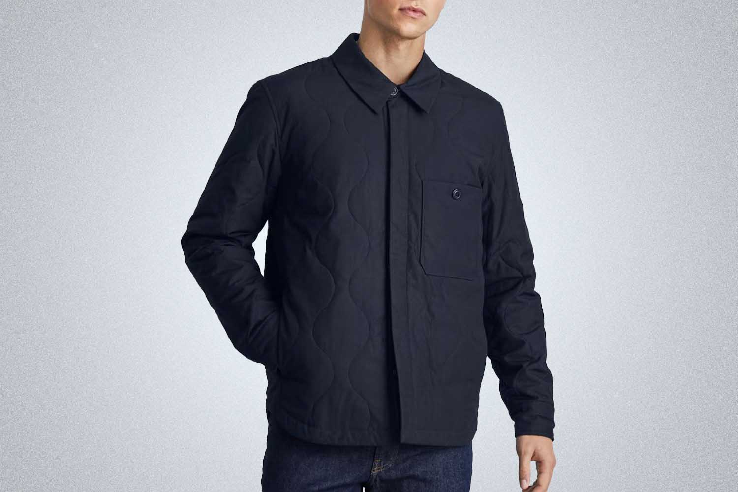a model wearing a liner lightweight jacket from Everlane on a grey background