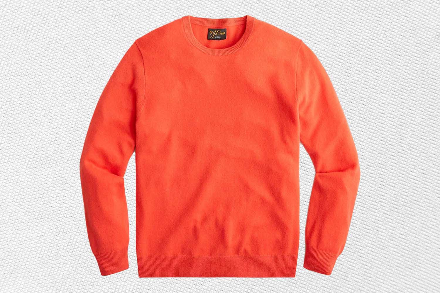 an orange cashmere sweater from J.Crew on a textured white background