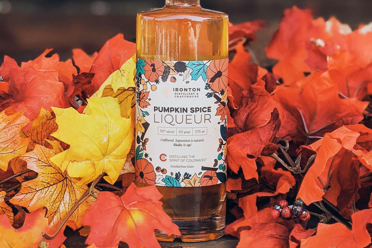 a pumpkin spice liqueur against fall foliage