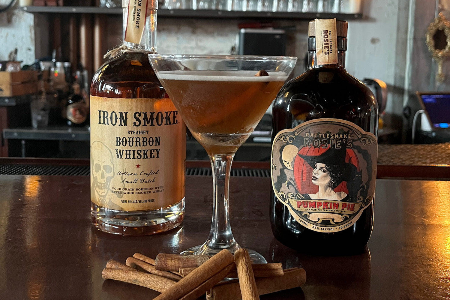 a cocktail on a bar in front of two diffrent liquor bottles