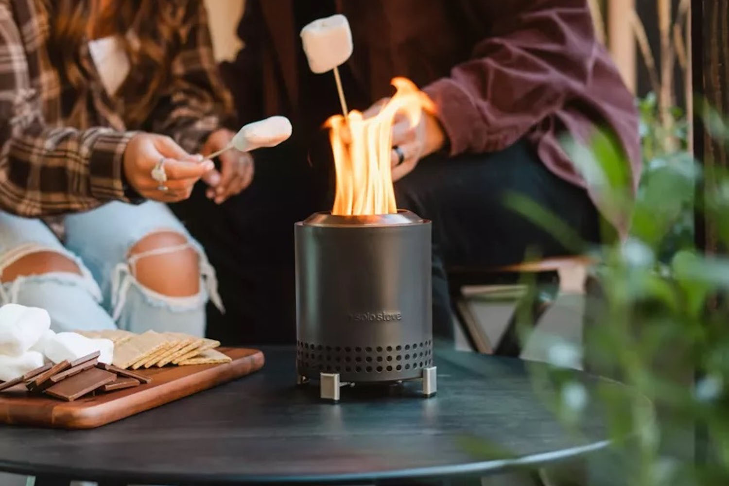 a table top solo stove mesa on a table with people roasting marshmellows