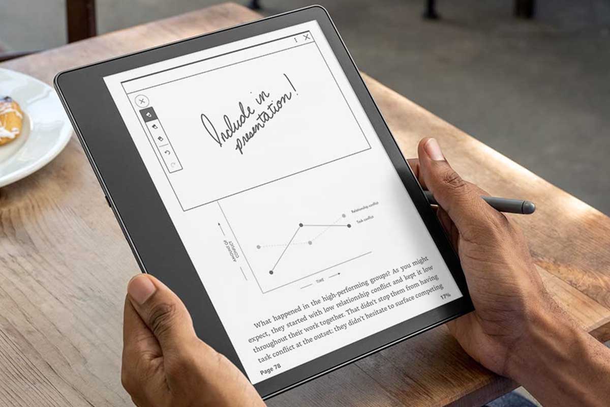 A person holding a Kindle Scribe and taking notes with a pen on the device