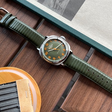 The Shinola Mechanic hand-wound watch in olive green sitting on a table. We tested and reviewed the new timepiece