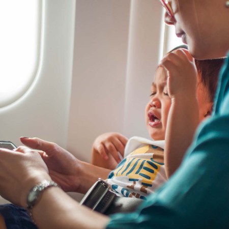 A mother and a crying baby watching a video in an airplane. Should babies be allowed on airplanes?
