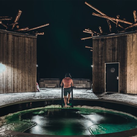 A man climbing out of the almost frozen river in the middle of the pool at Arctic Bath in Swedish Lapland