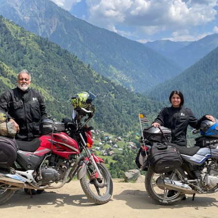 Qazi and Ghazal Farooqi posing in front of their motorcycles in the mountains of pakistan