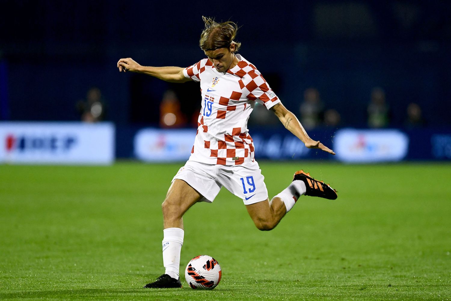 a player in a red and white checked soccer jersey
