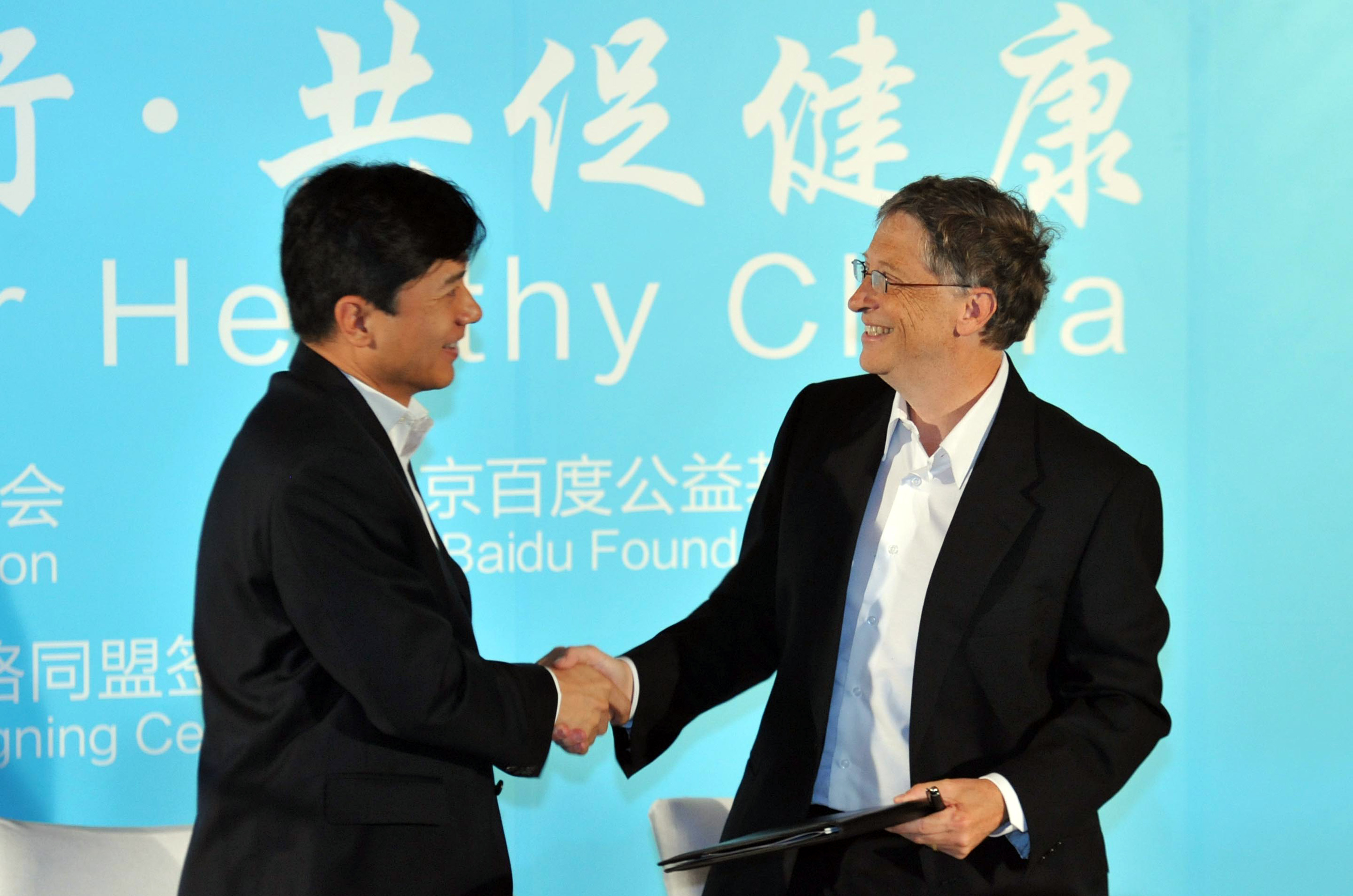 Robin Li and Bill Gates shaking hands at a conference.
