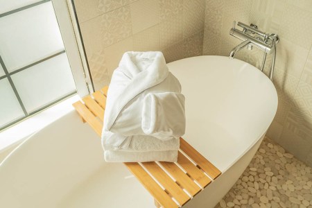 Robe and towels from FluffCo on top of a bath