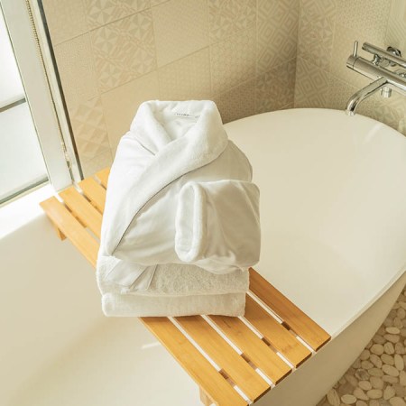 Robe and towels from FluffCo on top of a bath