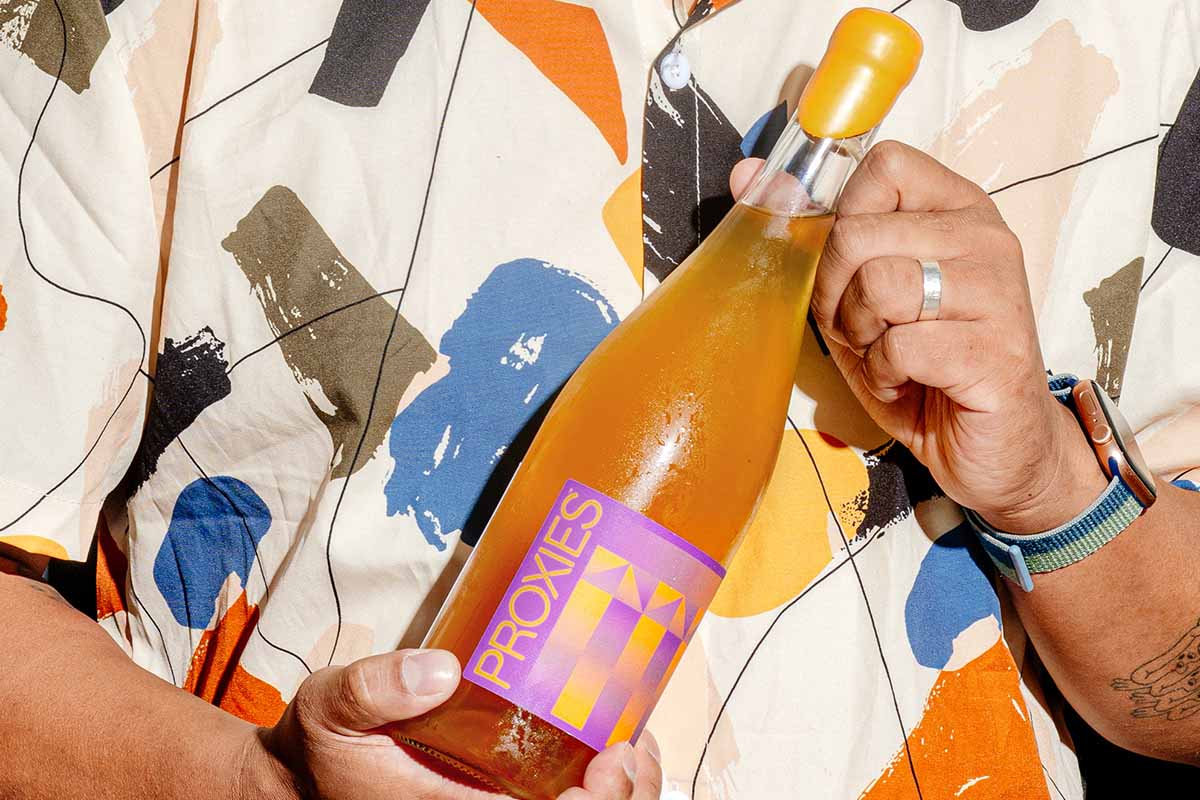 A man holding a bottle of Proxies Vinta non-alcoholic wine