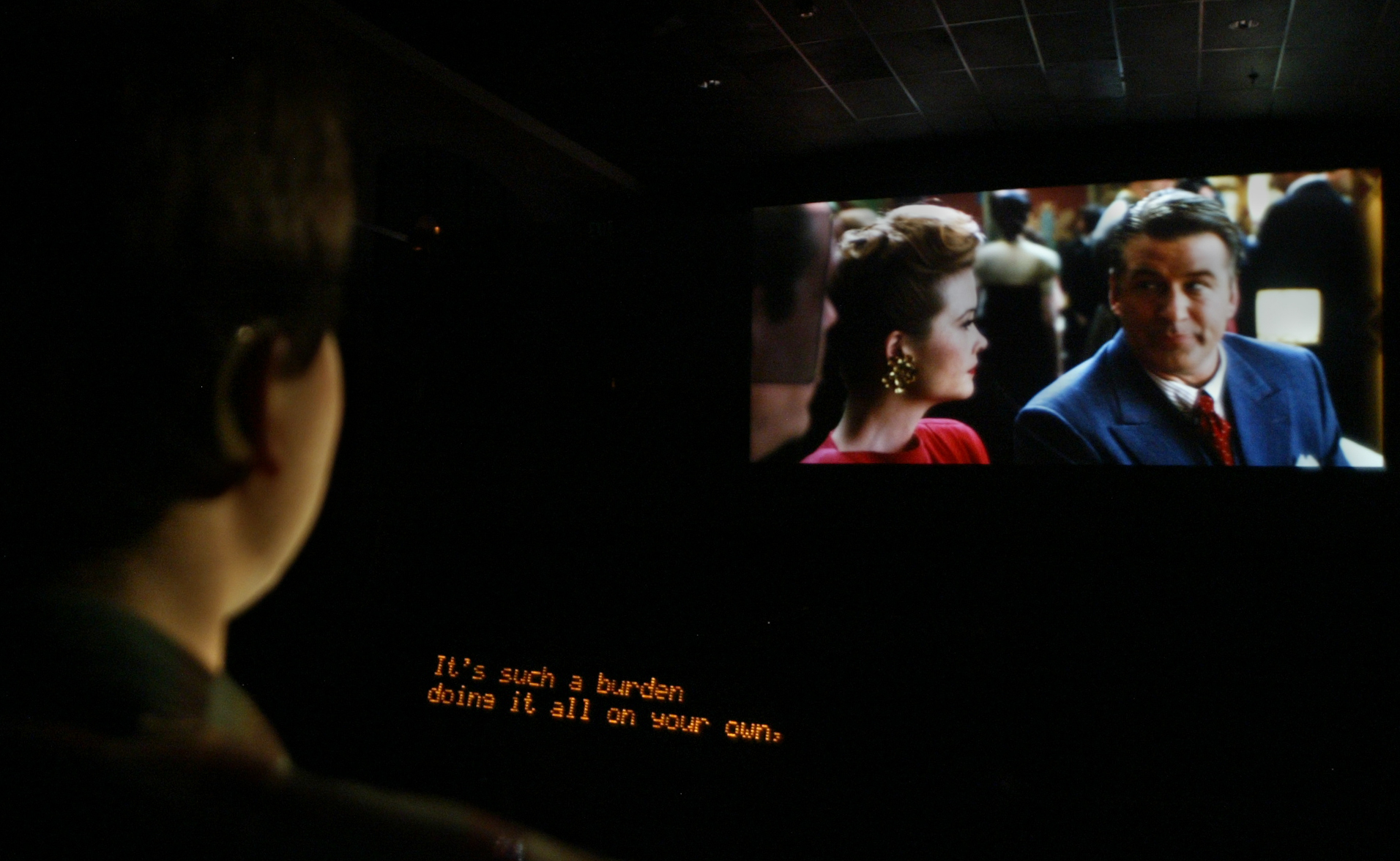 A picture of a man watching TV with closed captioning on.