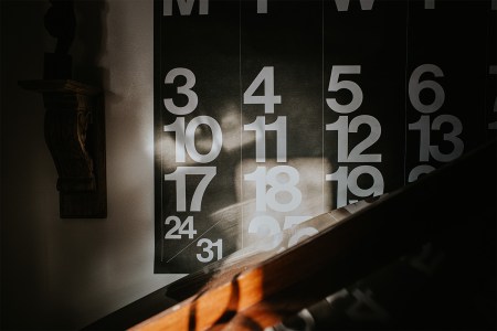 A large wall calendar is illuminated by warm sunbeams.
