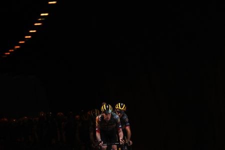 A Belgian cycling team emerges from a dark tunnel.