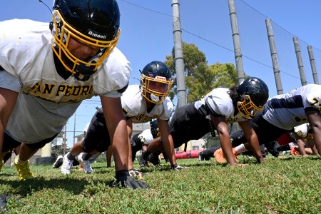 Members of a high school football team doing push-ups.