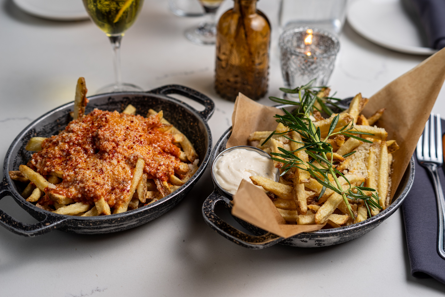 Two bowls of fries with different toppings on each